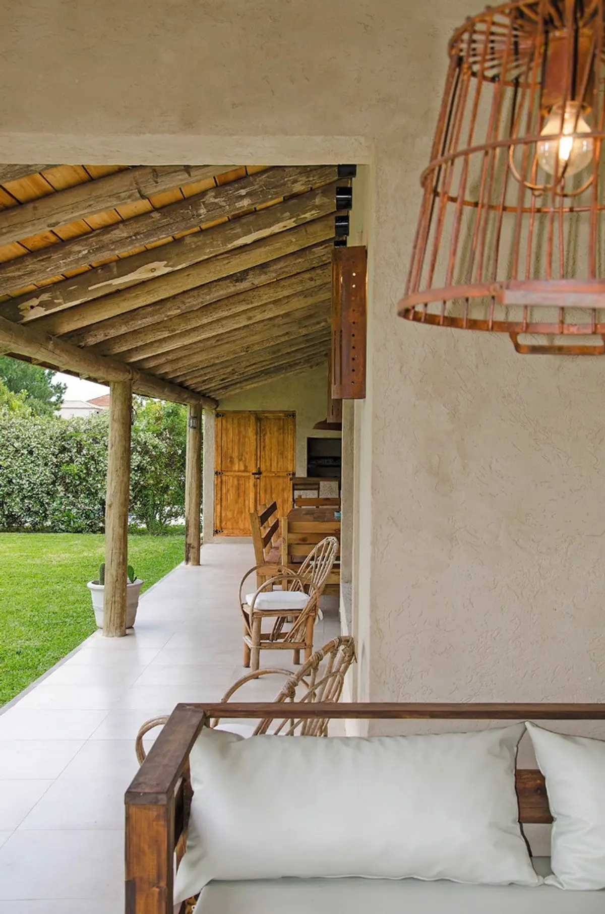 Varanda rústica com lustre de vime e móveis de rattan — projeto Casa 13, por Estudio Martínez Nespral