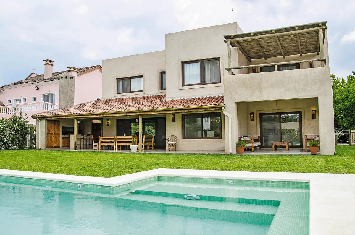 Fachada moderna com piscina, deck de madeira e detalhes em pedra — projeto Casa 13, por Estudio Martínez Nespral