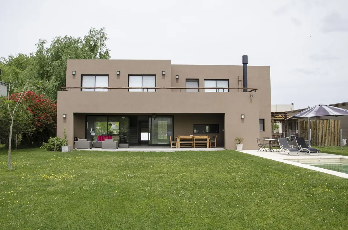 fachada moderna com gramado extenso e móveis externos — projeto Casa 12, por Estudio Martínez Nespral