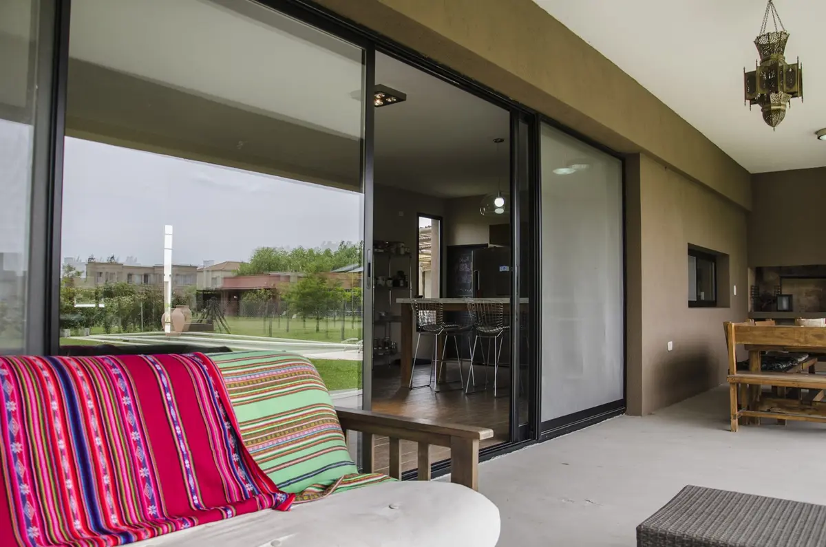 Pátio moderno com sofá listrado e cozinha integrada — projeto Casa 12, por Estudio Martínez Nespral