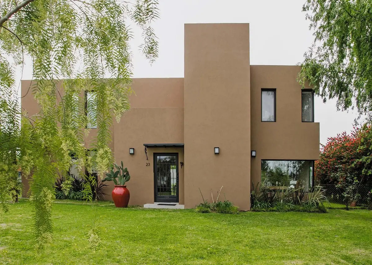 fachada moderna de casa com estuque bege e vegetação proeminente — projeto Casa 12, por Estudio Martínez Nespral