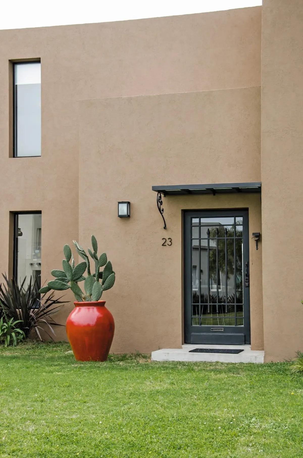 Fachada moderna com cacto e porta de ferro forjado — projeto Casa 12, por Estudio Martínez Nespral