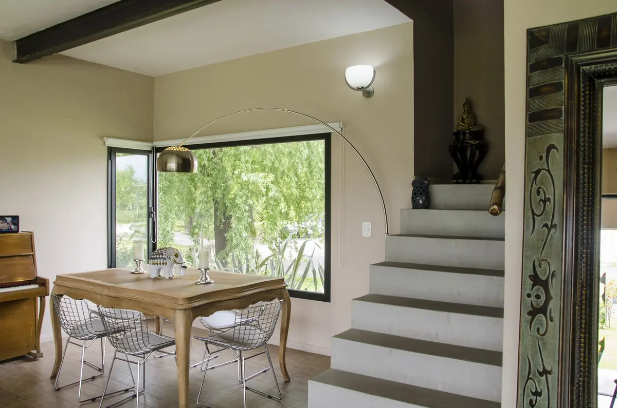 Sala de jantar moderna com janelas do chão ao teto e escada flutuante — projeto Casa 12, por Estudio Martínez Nespral