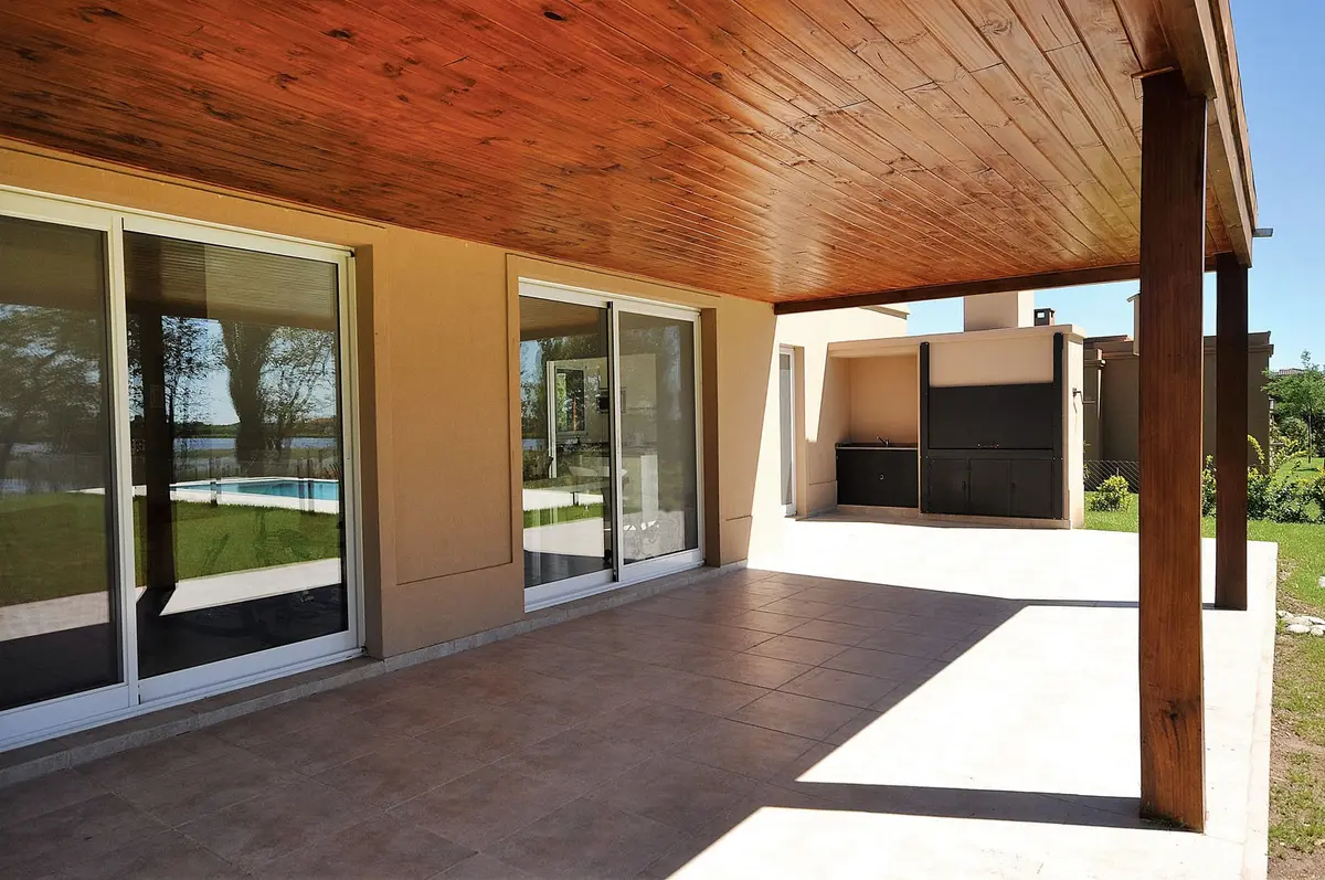 Amplo pátio moderno com pérgola de madeira e janelas de vidro — projeto Casa 11, por Estudio Martínez Nespral