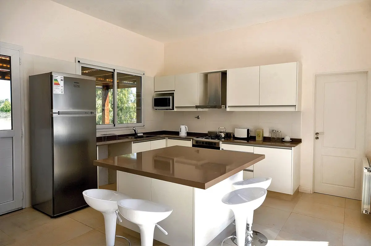 Cozinha moderna aberta com ilha central e eletrodomésticos em aço inoxidável — projeto Casa 11, por Estudio Martínez Nespral