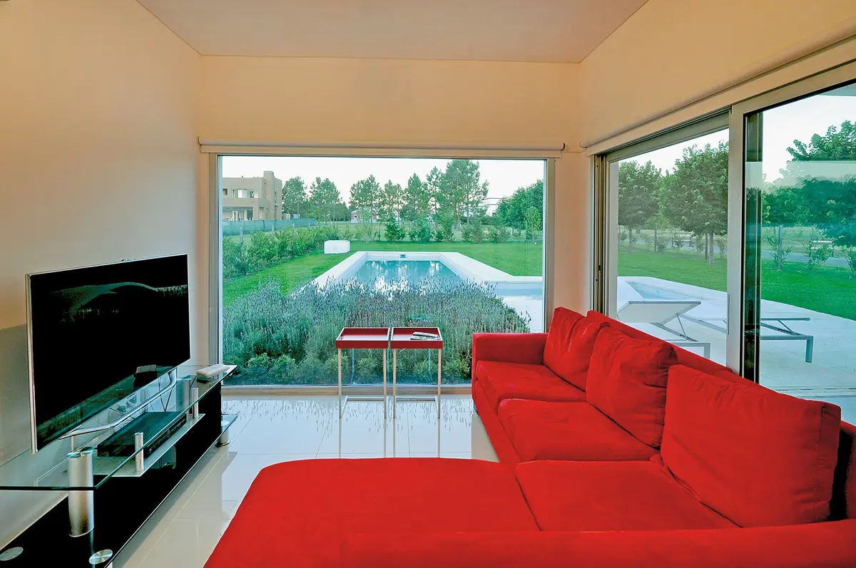 Sala de estar moderna com sofá vermelho e vista para o jardim — projeto Casa 10, por Estudio Martínez Nespral