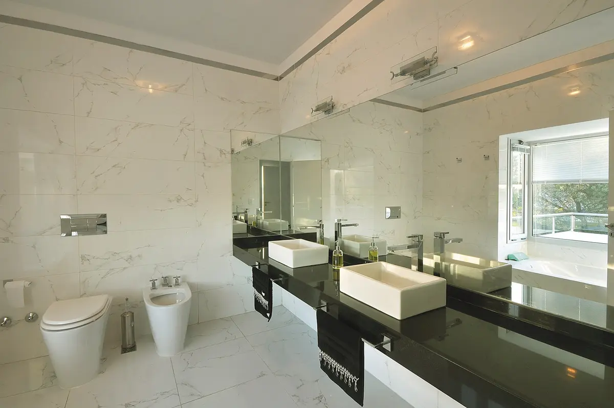 Baño moderno con doble bacha, paredes de mármol y mesada negra — proyecto Casa 10, por Estudio Martínez Nespral