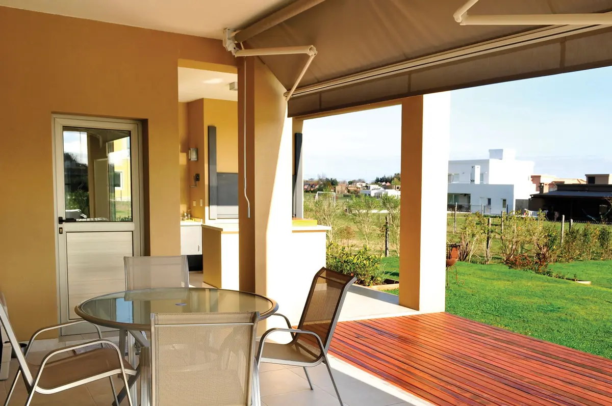 Pátio com deck de madeira, móveis transparentes e vista verde — projeto Casa 8, por Estudio Martínez Nespral