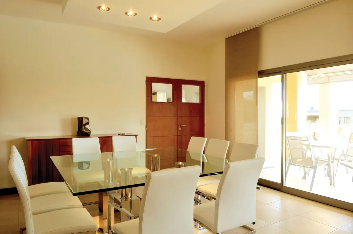 Comedor moderno con mesa de vidrio y sillas blancas, buffet de madera — proyecto Casa 8, por Estudio Martínez Nespral