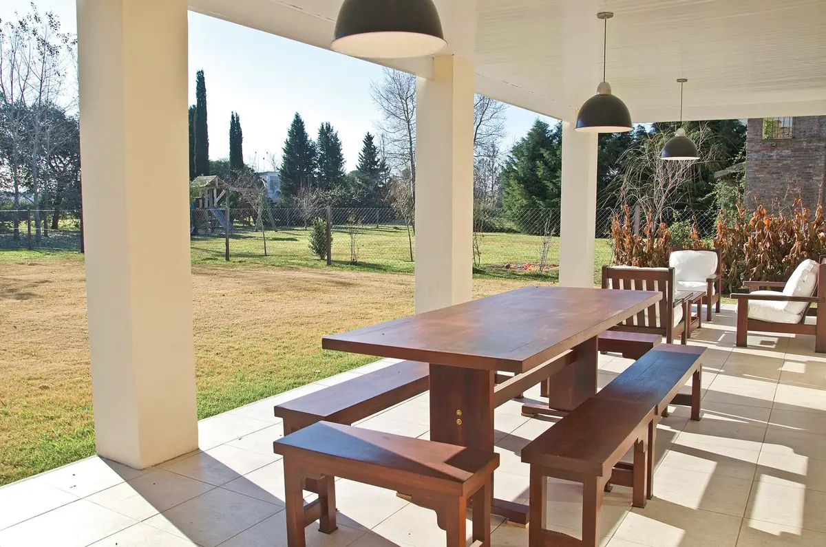 Patio cubierto con mesa de madera y pergola — proyecto Casa 7, por Estudio Martínez Nespral