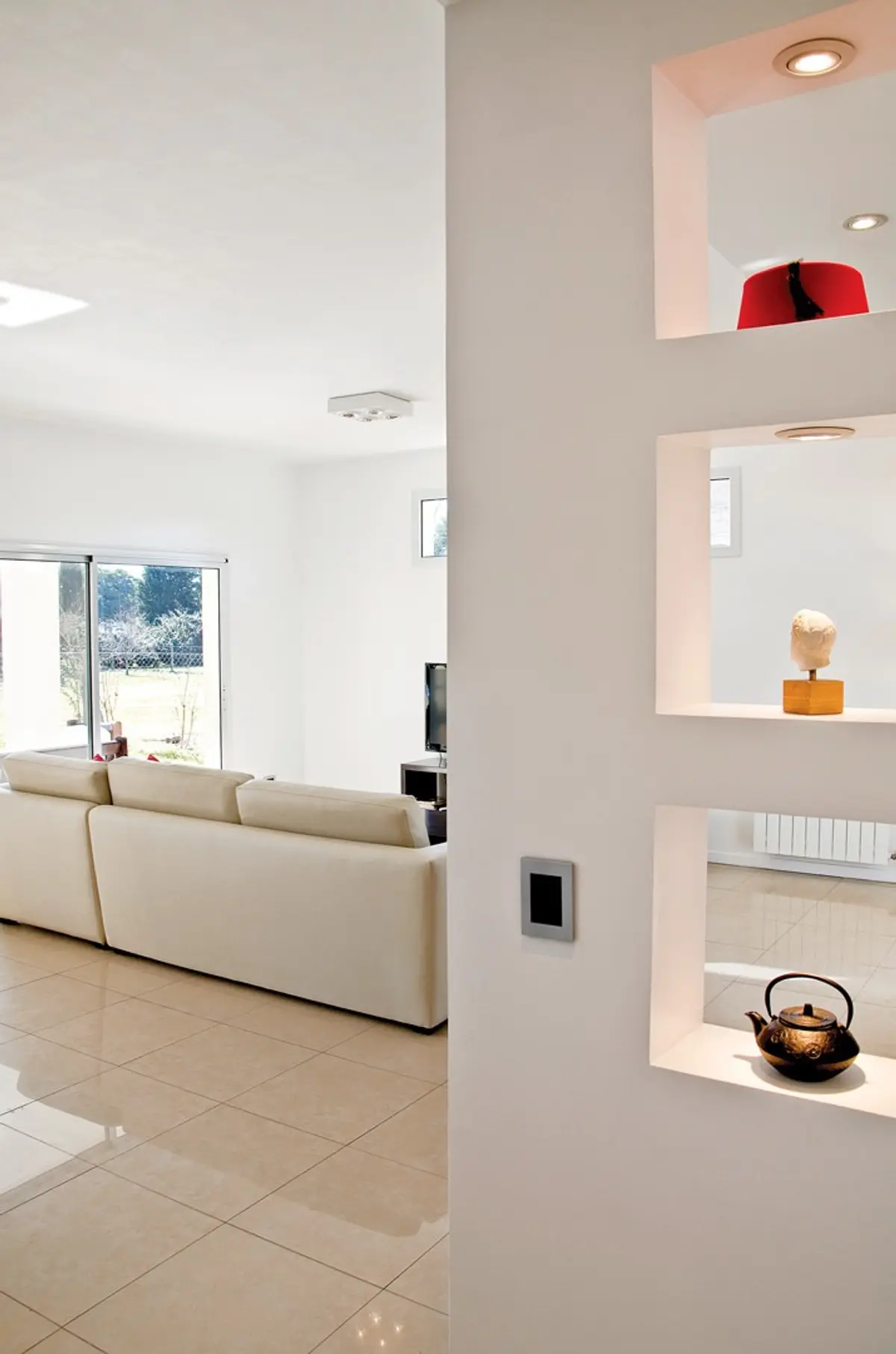 Sala de estar moderna com sofá branco e prateleiras embutidas — projeto Casa 7, por Estudio Martínez Nespral
