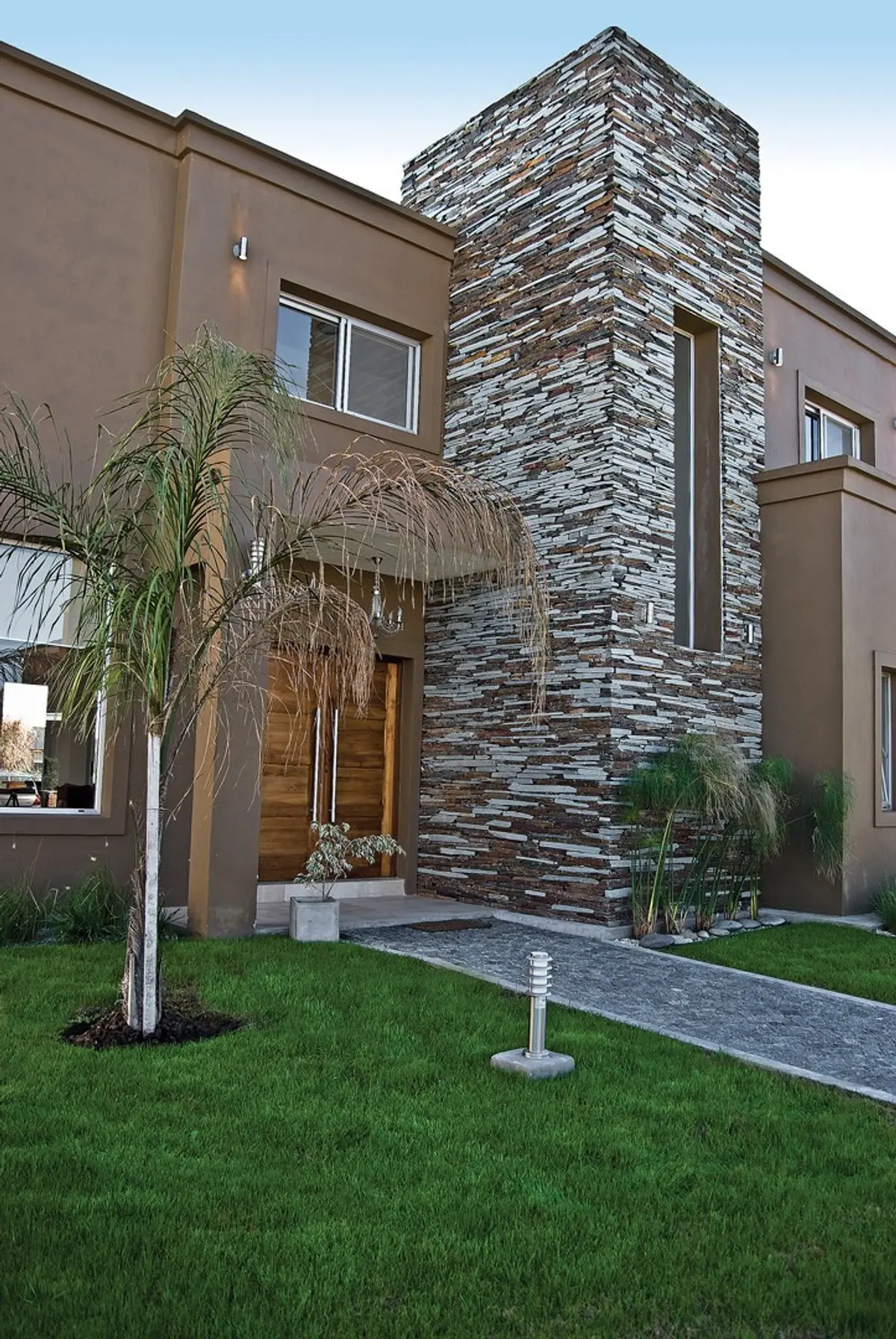 Fachada moderna com pedra empilhada e palmeira — projeto Casa 5, por Estudio Martínez Nespral
