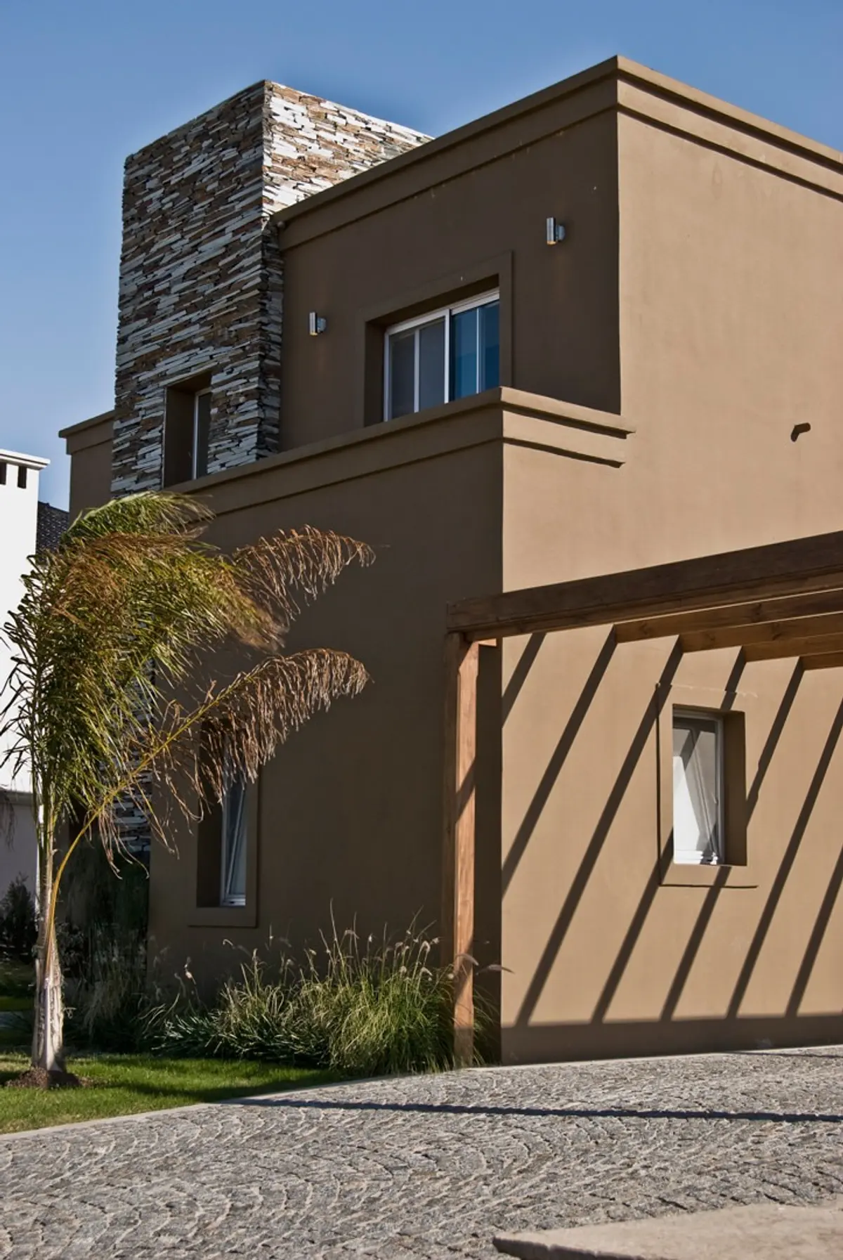 fachada moderna com pergolado e detalhes em pedra empilhada — projeto Casa 5, por Estudio Martínez Nespral