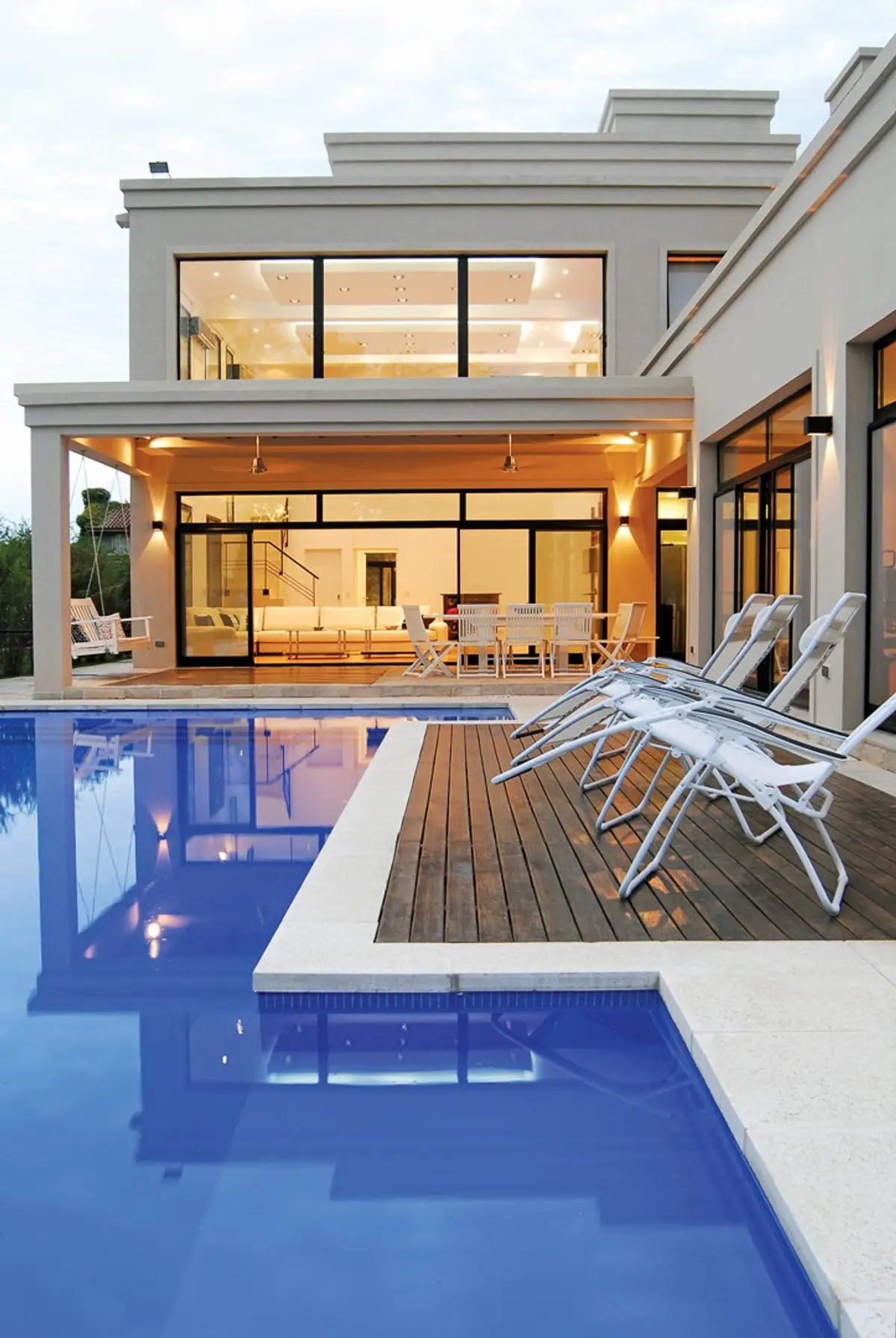 Piscina moderna com deck de madeira e cadeiras brancas — projeto Casa 3, por Estudio Martínez Nespral