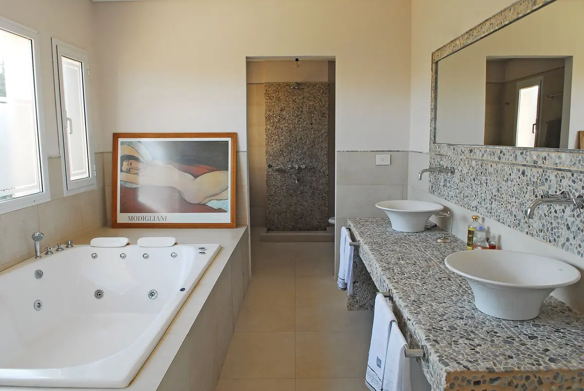 Banheiro espaçoso com jacuzzi, duas cubas e janelas amplas — projeto Casa 1, por Estudio Martínez Nespral