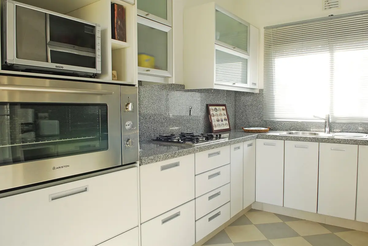 Cozinha moderna branca com eletrodomésticos embutidos e bancada de pedra — projeto Casa 1, por Estudio Martínez Nespral