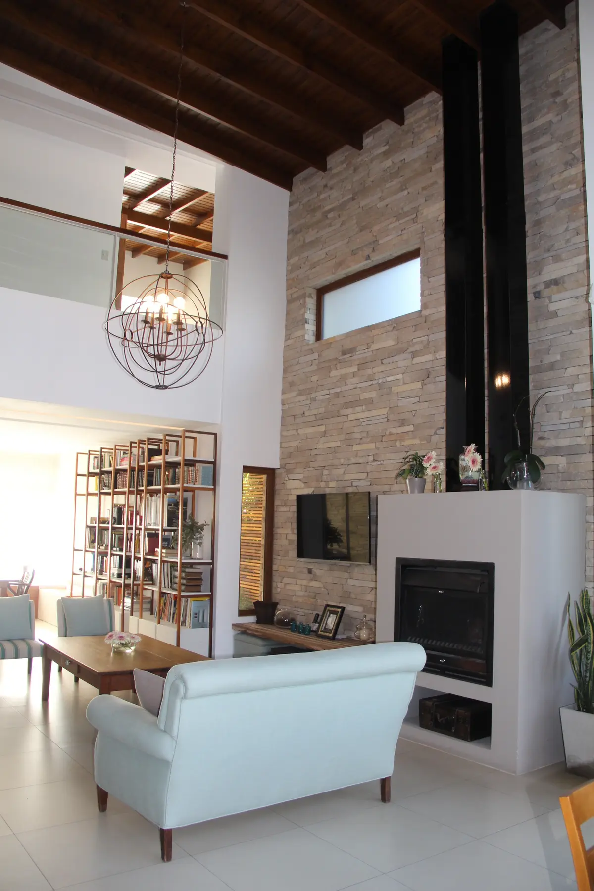 Living comedor moderno con techos de madera y pared de piedra — proyecto Casa Barrio Parque Luro, por Estudio Arq. Carolina Peruzzo , en Mar del Plata