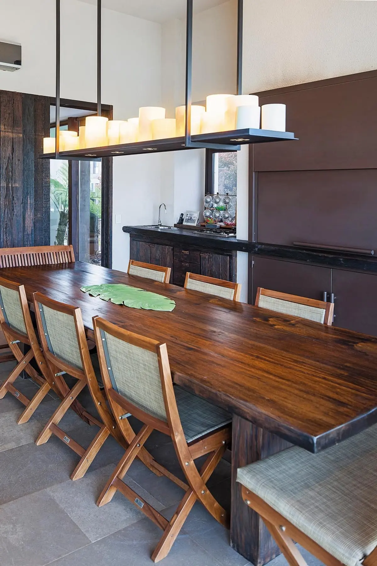Sala de jantar moderna com mesa de madeira viva e lustre linear — projeto Casa DFS, por Estudio Gamboa