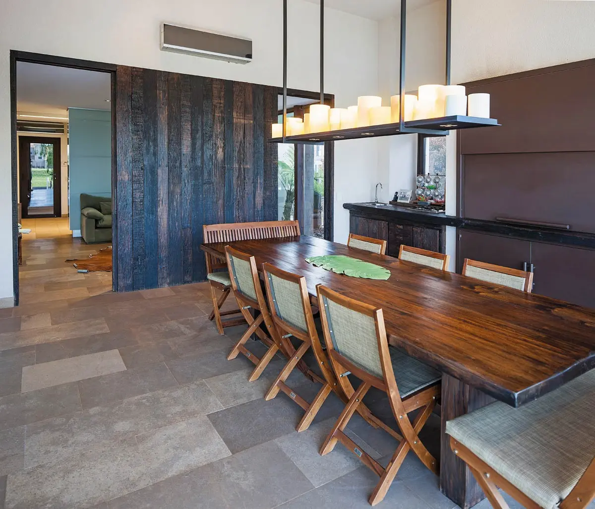 Sala de jantar moderna rústica com ilha de cozinha integrada e mesa de madeira — projeto Casa DFS, por Estudio Gamboa