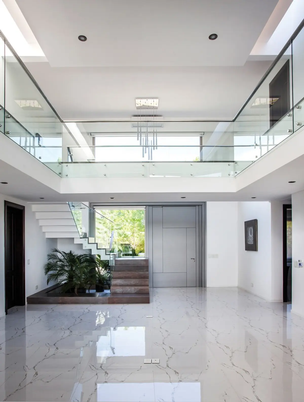 Atrio moderno con escalera flotante y suelo de mármol — proyecto Casa MSC, por Estudio Gamboa