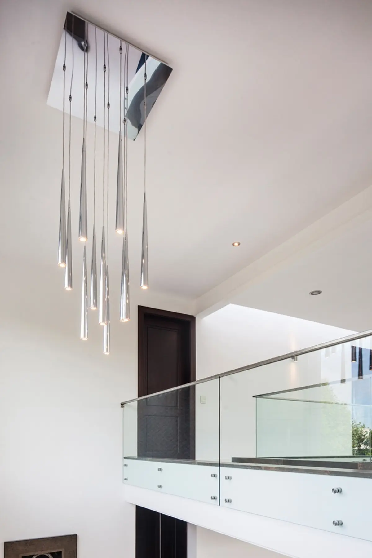 Lustre moderno em cascata em escada flutuante com corrimão de vidro — projeto Casa MSC, por Estudio Gamboa