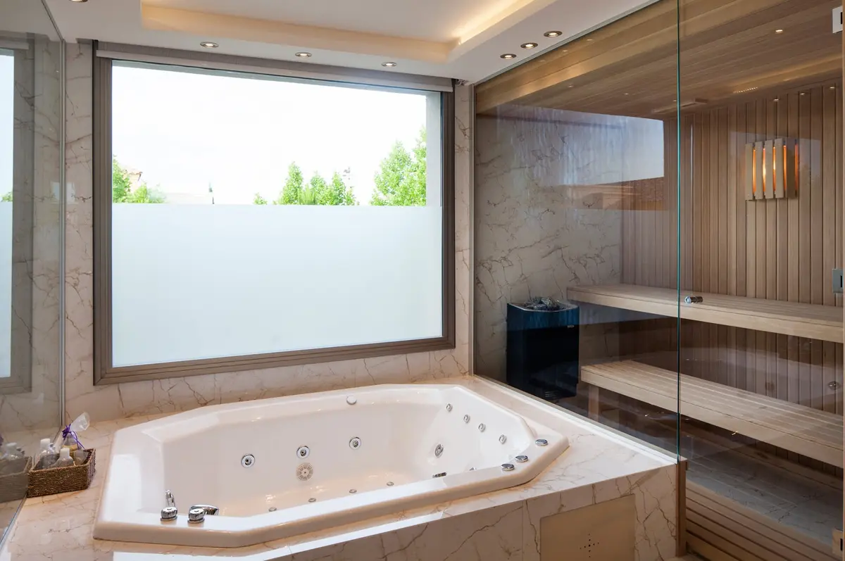 Banheiro de luxo com jacuzzi, sauna e janela panorâmica — projeto Casa MSC, por Estudio Gamboa