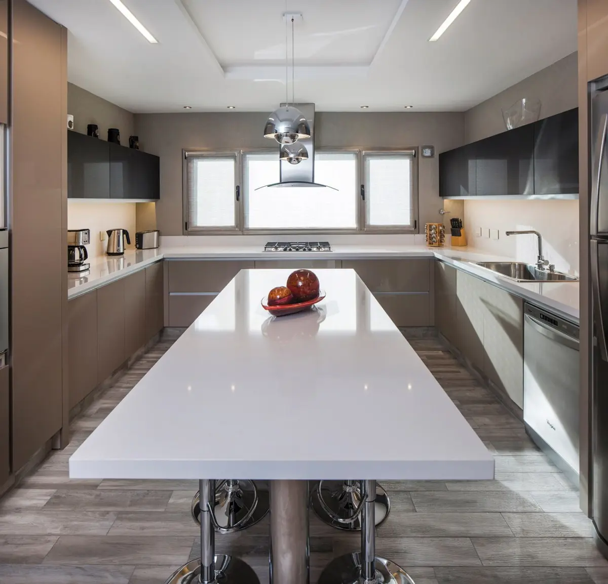 Cozinha moderna aberta com ilha grande de mármore branco e banquetas — projeto Casa MSC, por Estudio Gamboa