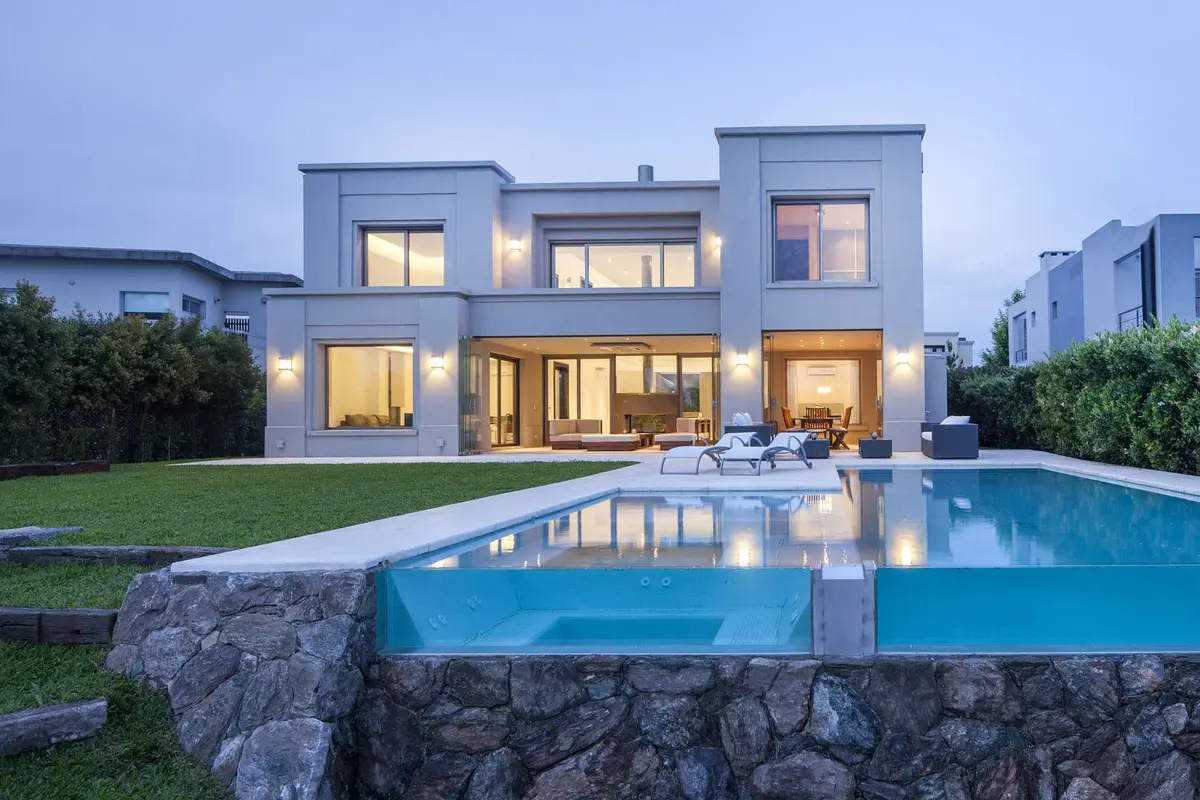 Fachada moderna com piscina de borda infinita e luzes quentes ao entardecer — projeto Casa MSC, por Estudio Gamboa
