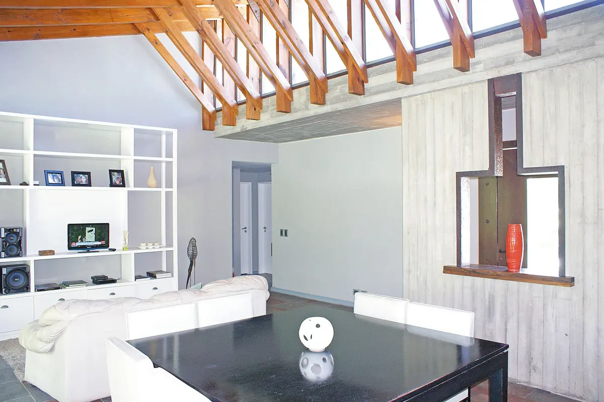 Sala de estar moderna com vigas de madeira aparente e estante branca — projeto Casa CP, por Estudio Gamboa