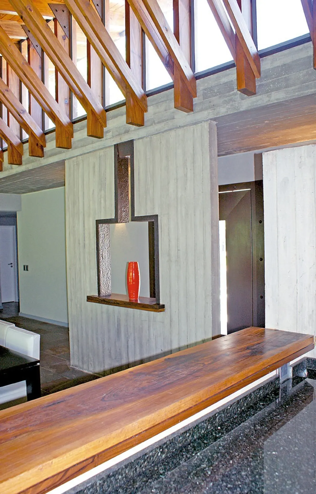 Sala moderna com concreto aparente, vigas de madeira e banco de madeira — projeto Casa CP, por Estudio Gamboa