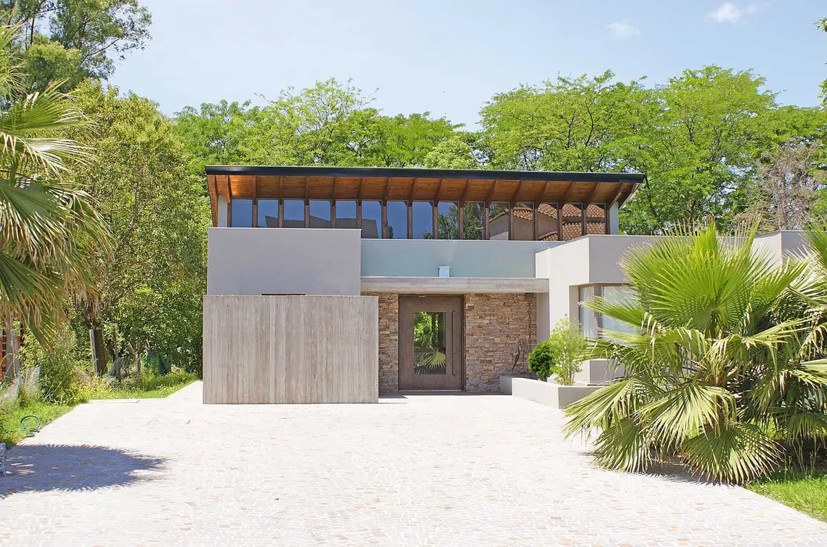 Fachada moderna com concreto, madeira e amplas janelas — projeto Casa CP, por Estudio Gamboa