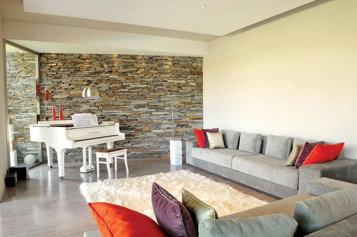 Living moderno con piano blanco y pared de piedra — proyecto Casa GGG, por Estudio Gamboa