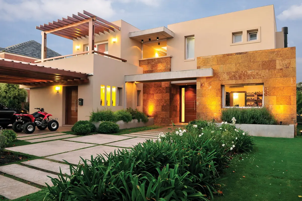 Casa moderna con fachada de piedra y jardín exuberante — proyecto Casa GTT, por Estudio Gamboa