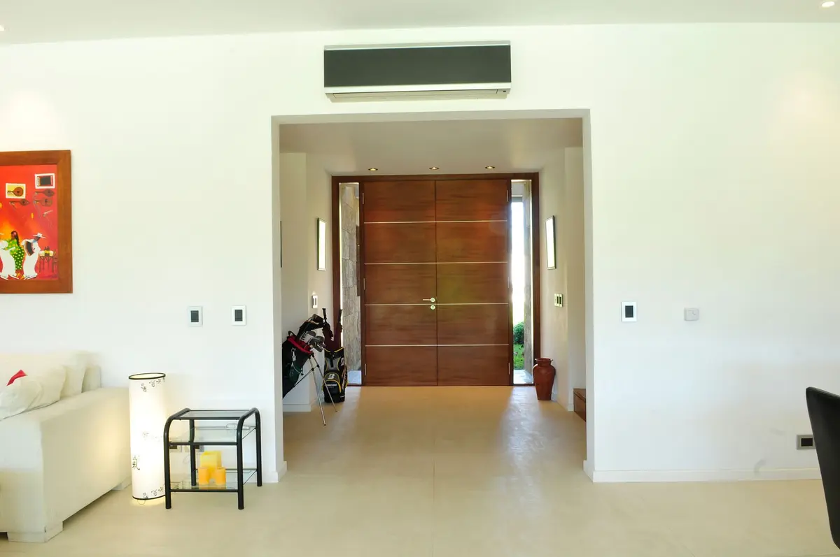 corredor moderno com portas duplas de madeira e sofá branco — projeto Casa GTT, por Estudio Gamboa