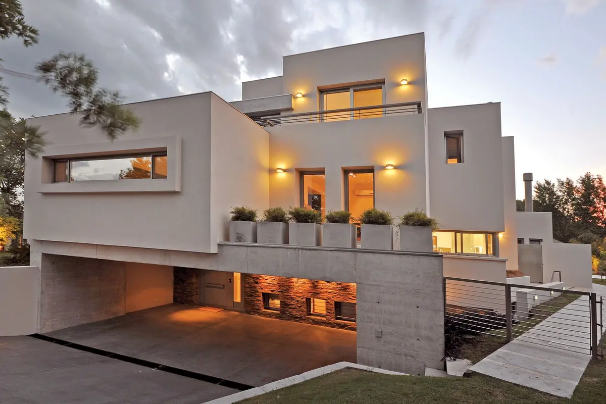 Fachada moderna con grandes ventanales y luces cálidas — proyecto Casa MMP, por Estudio Gamboa