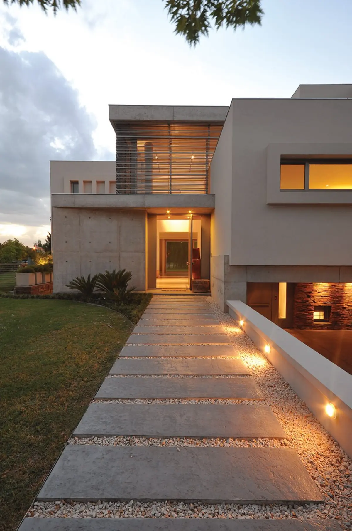 Fachada moderna com caminho de concreto e iluminação integrada — projeto Casa MMP, por Estudio Gamboa