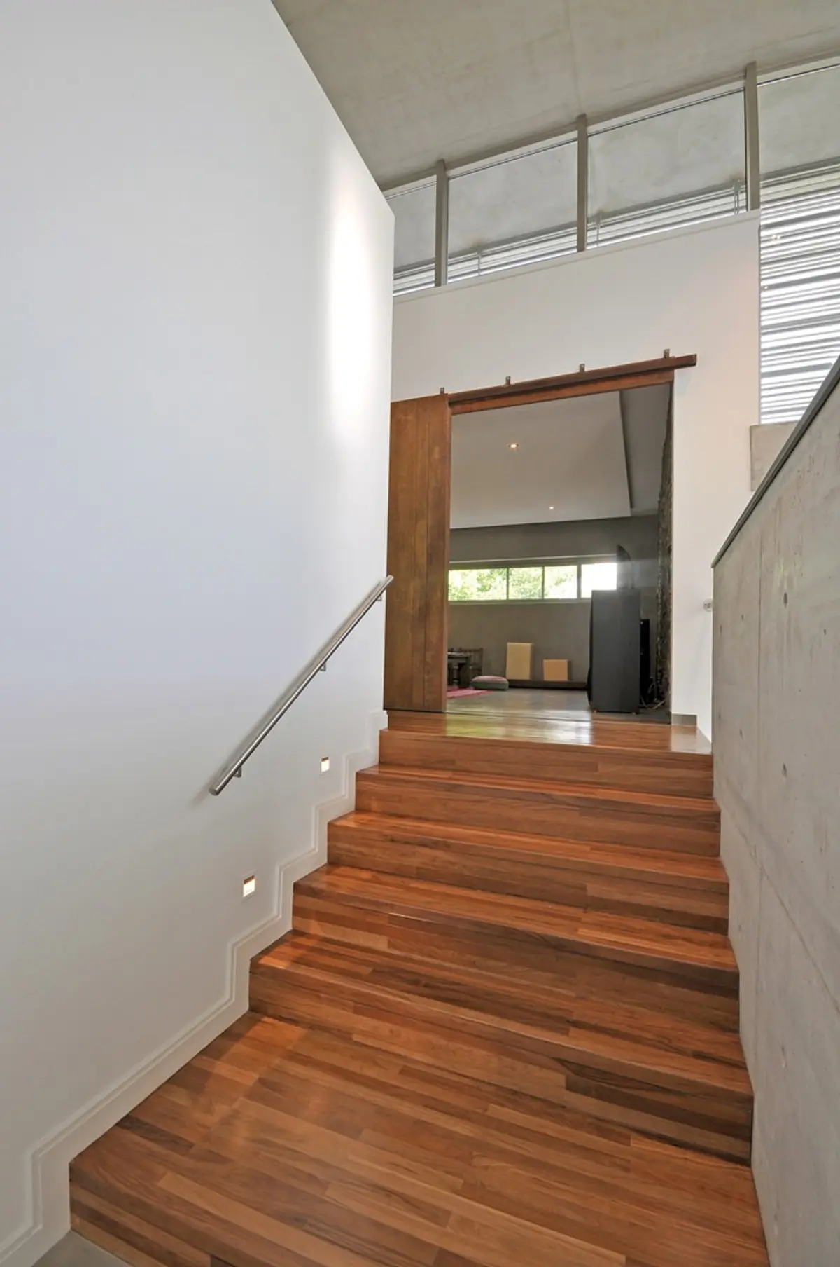 Escalera moderna de madera con baranda de acero inoxidable y luces — proyecto Casa MMP, por Estudio Gamboa