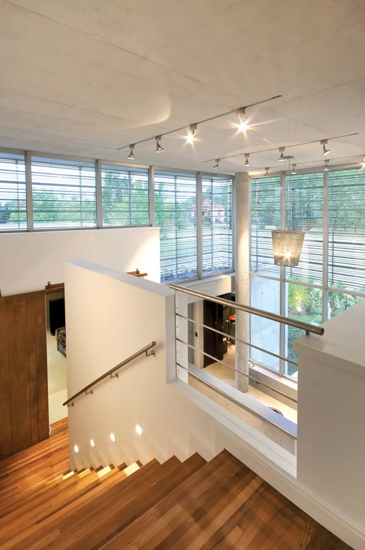 Escada flutuante moderna com piso de madeira e janelas do chão ao teto — projeto Casa MMP, por Estudio Gamboa