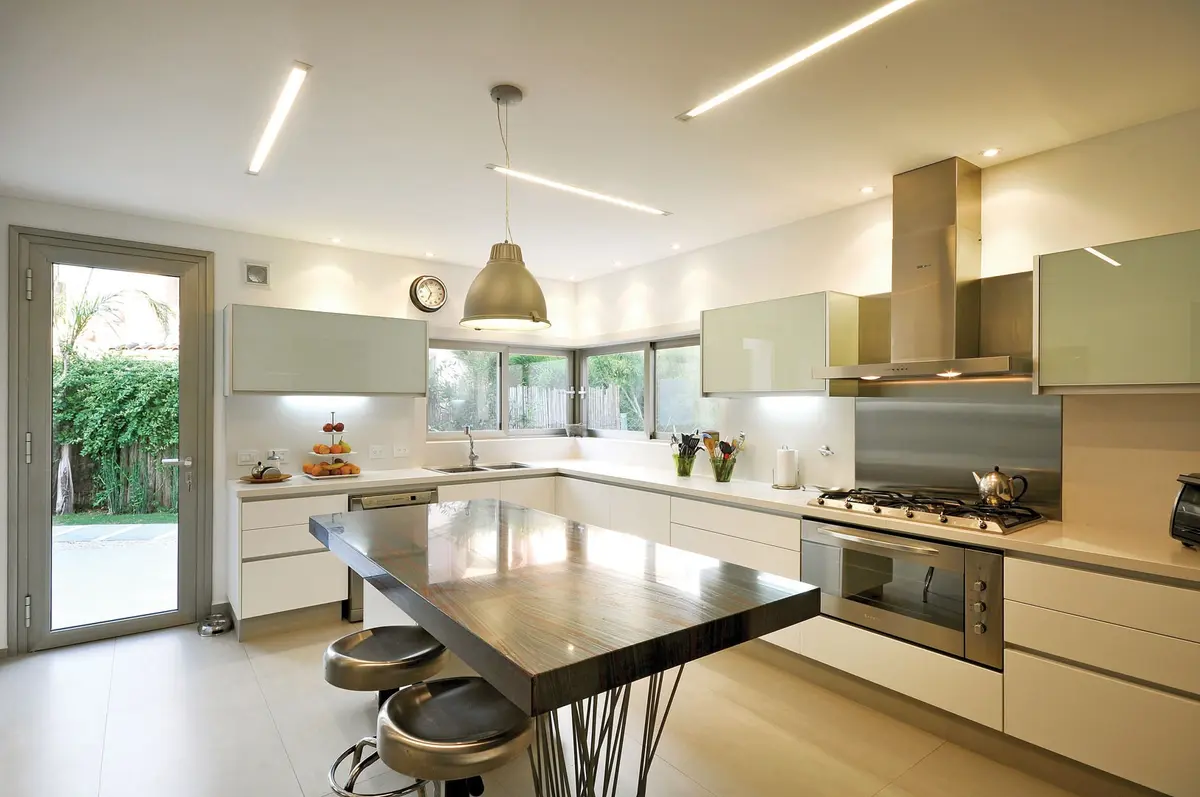 Cozinha moderna e aberta com ilha grande e detalhes metálicos — projeto Casa MMP, por Estudio Gamboa
