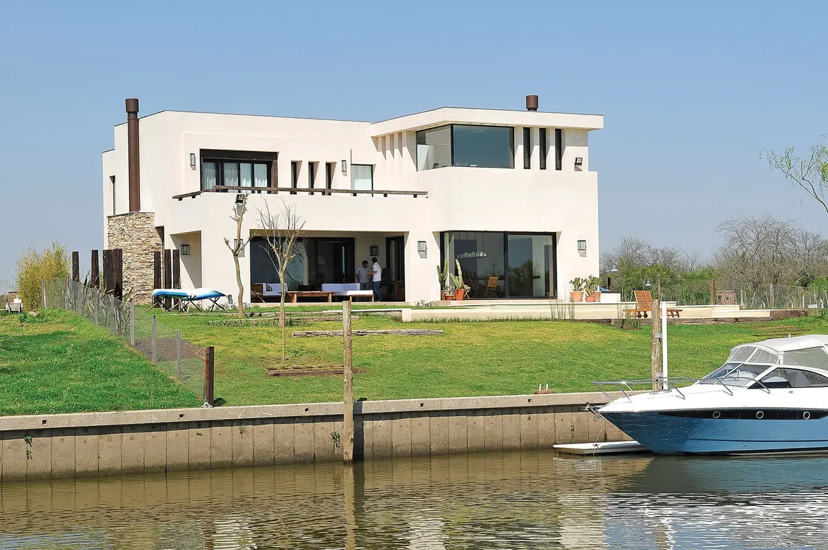 casa moderna em frente ao canal com iate de luxo — projeto Casa Tigre, por Estudio Gamboa, em Tigre