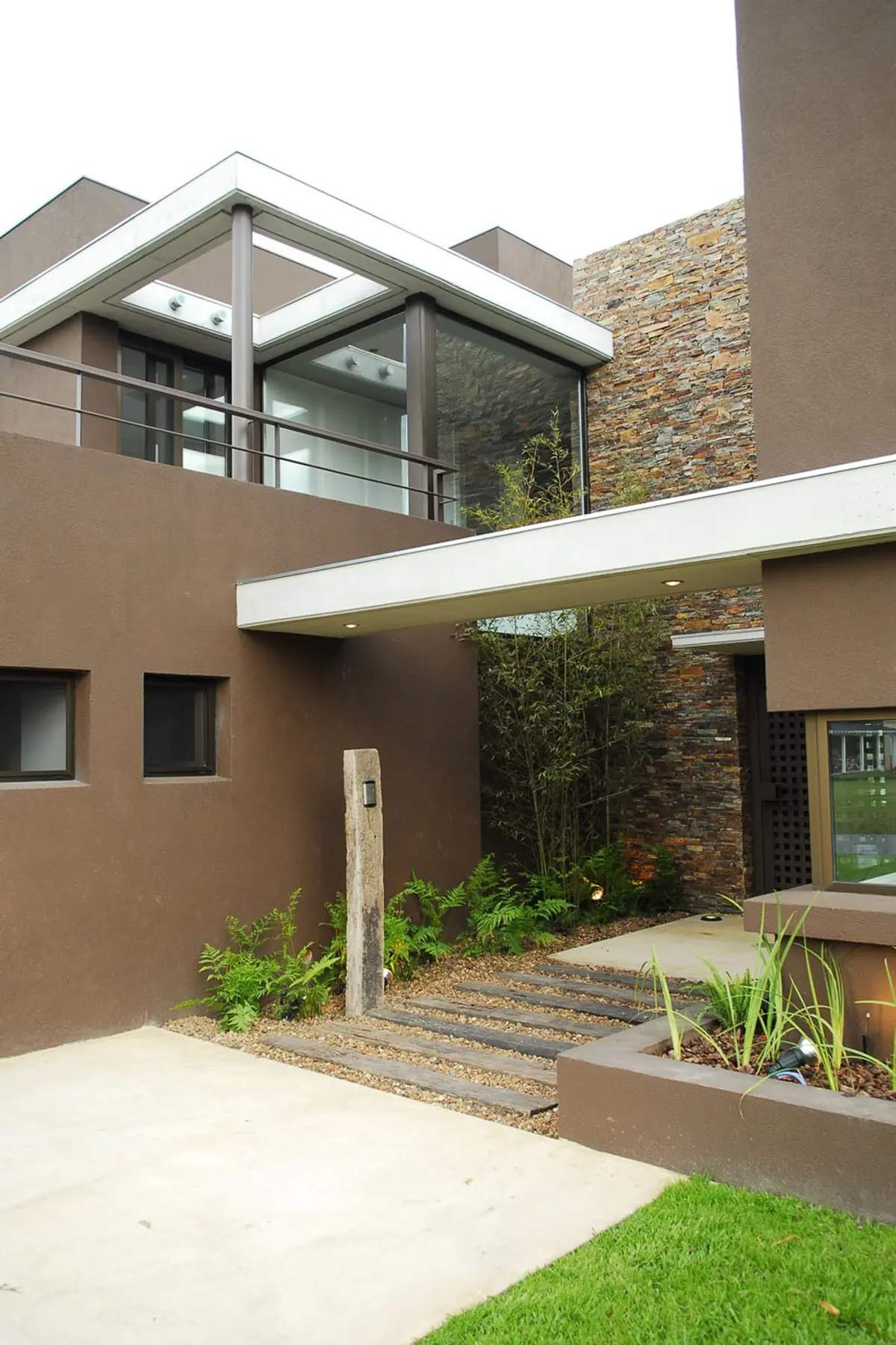Fachada moderna con detalles en piedra y jardín minimalista — proyecto Casa RFM, por Estudio Gamboa