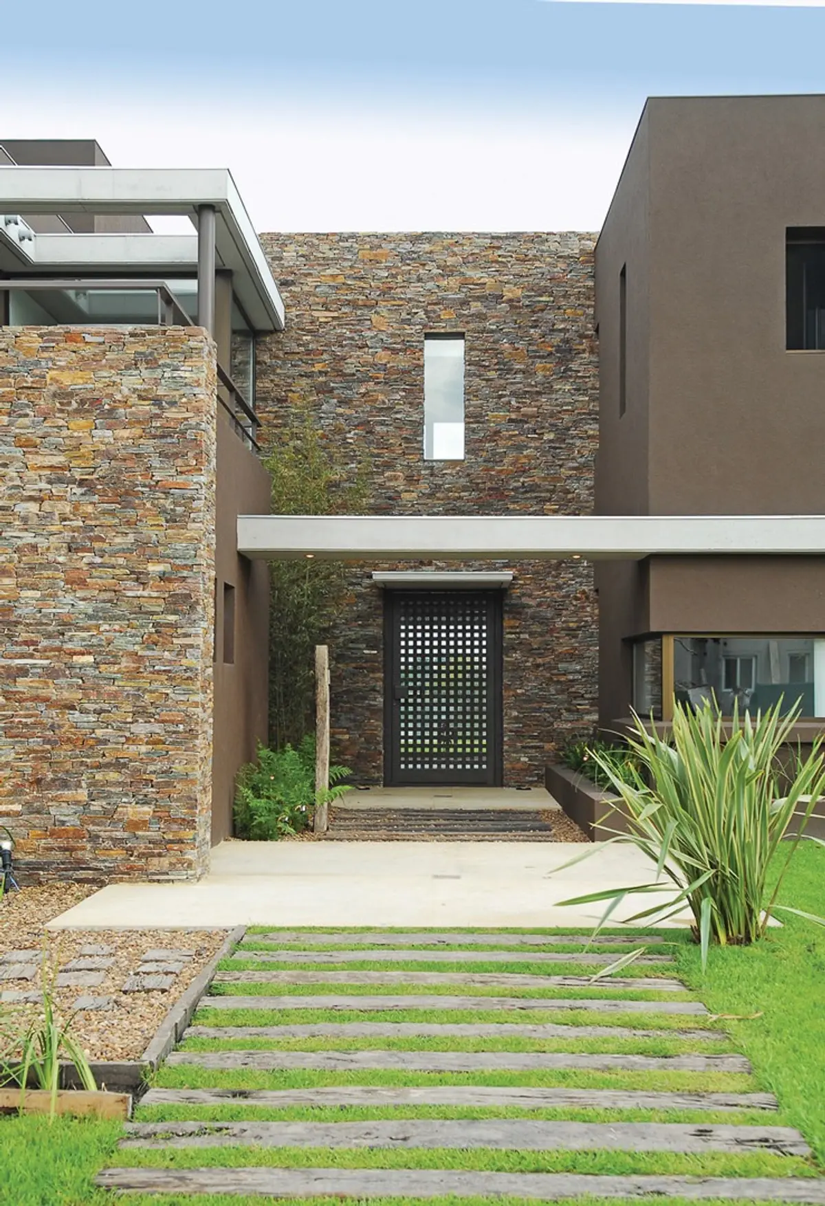 Fachada moderna con piedra apilada y camino de madera — proyecto Casa RFM, por Estudio Gamboa