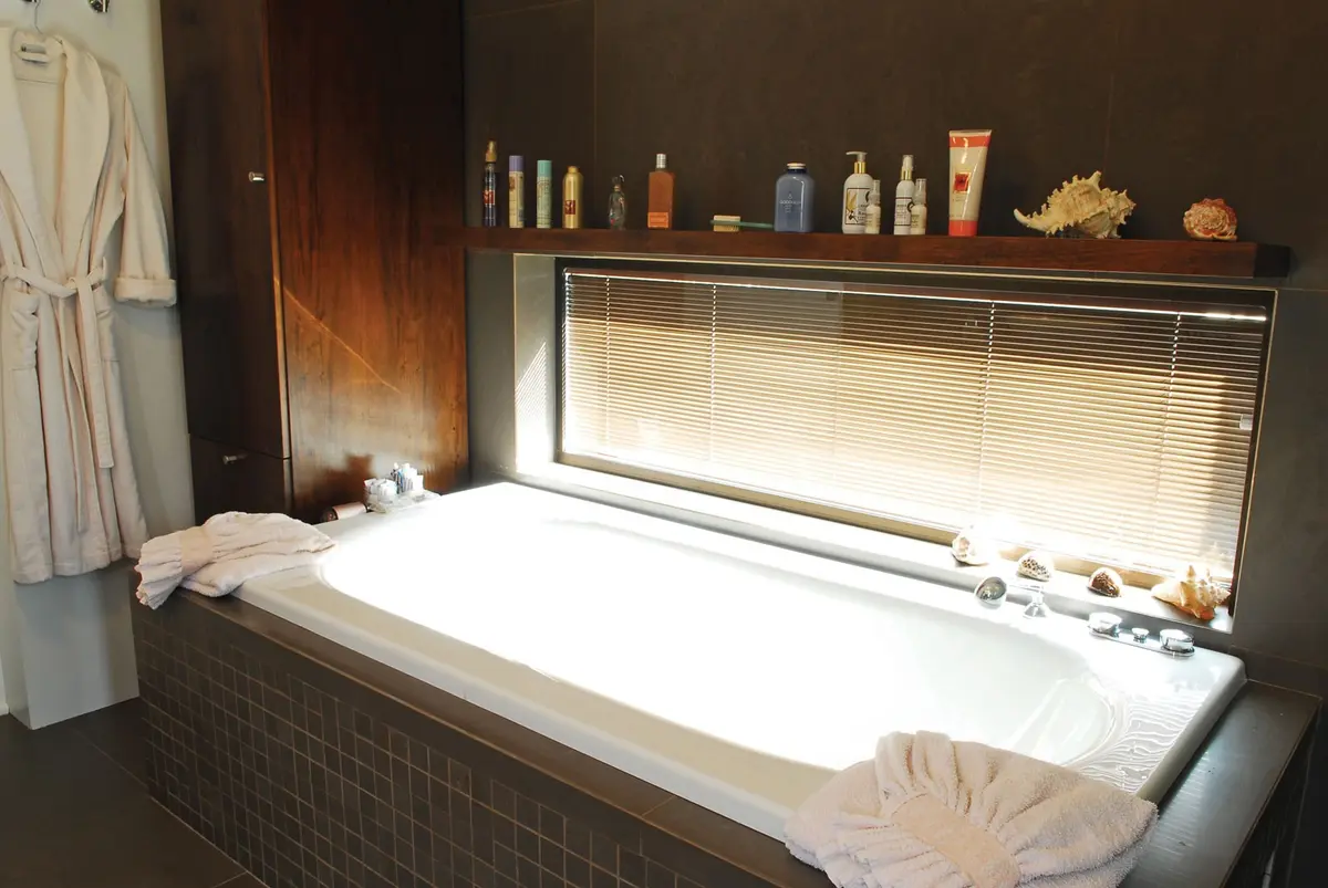 Baño moderno con bañera exenta, ventana panorámica y pared texturizada — proyecto Casa RFM, por Estudio Gamboa