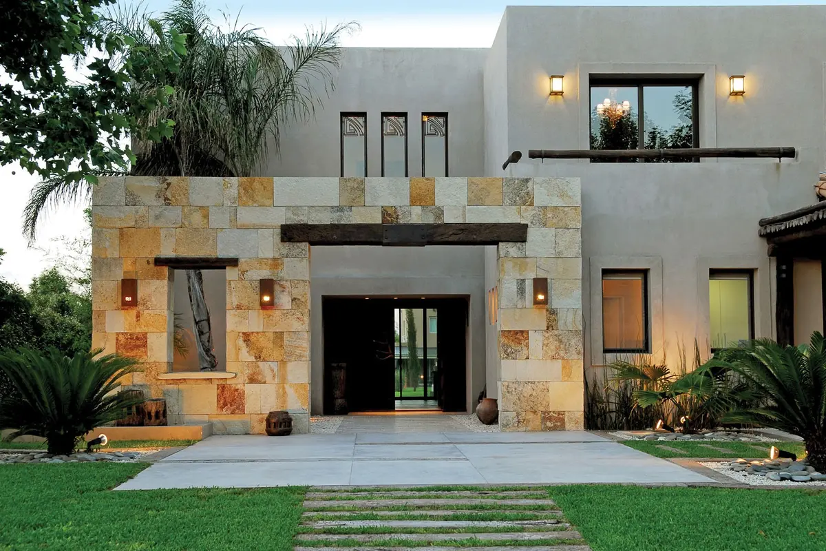 Fachada moderna con bloques de piedra y vegetación exuberante — proyecto Casa FGR, por Estudio Gamboa