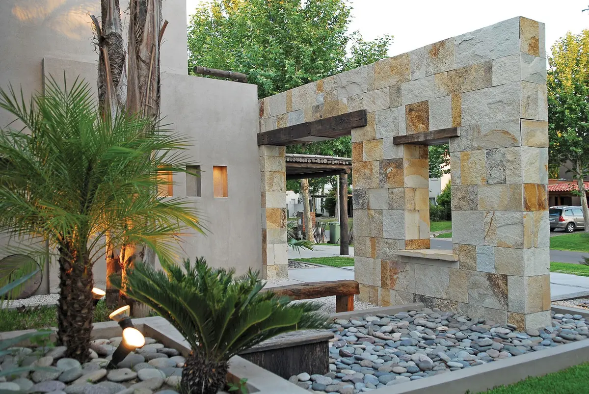 Fachada moderna com pedra, madeira e vegetação — projeto Casa FGR, por Estudio Gamboa