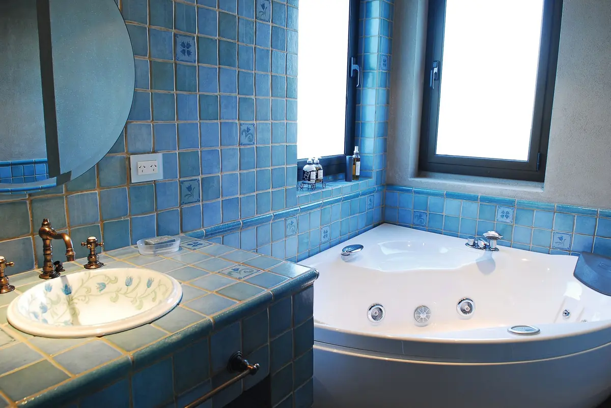 Baño con azulejos azules, bañera jacuzzi y grifería de latón — proyecto Casa FGR, por Estudio Gamboa