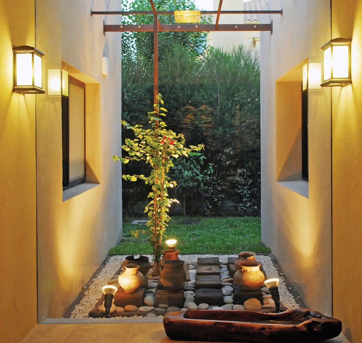Pátio zen com vegetação e iluminação quente — projeto Casa FGR, por Estudio Gamboa
