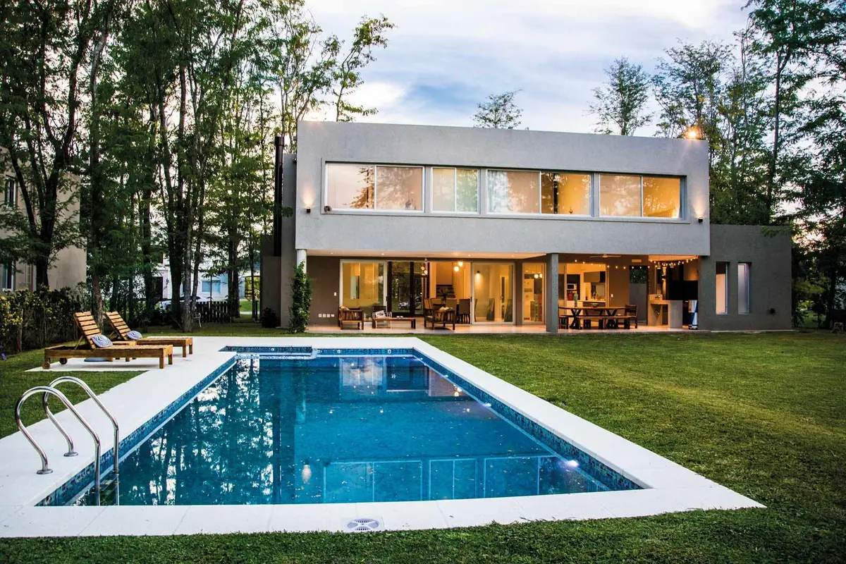 Casa moderna con pileta frente a fachada de hormigón y vidrio — proyecto Casa 18, por Parrado Arquitectura