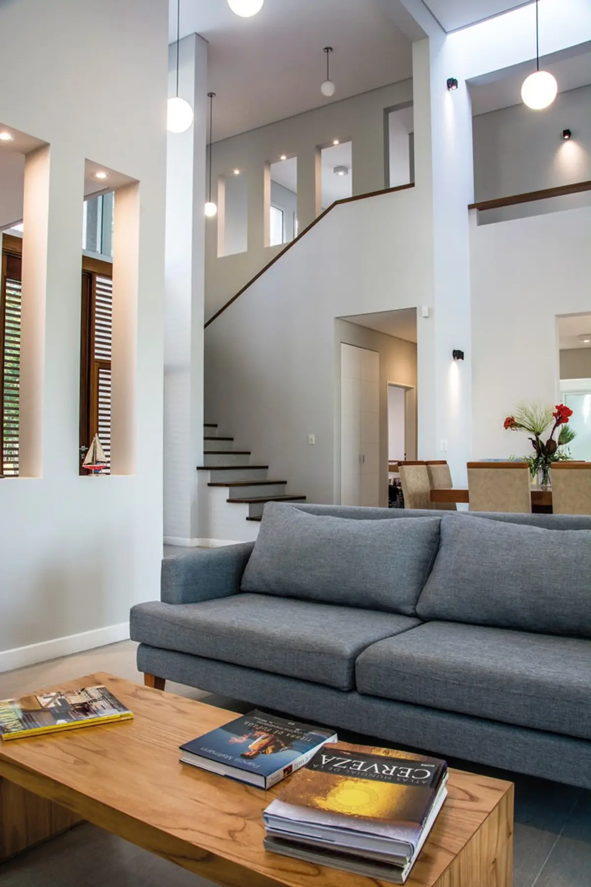 Living moderno con doble altura, sofá gris y escalera flotante — proyecto Casa 18, por Parrado Arquitectura