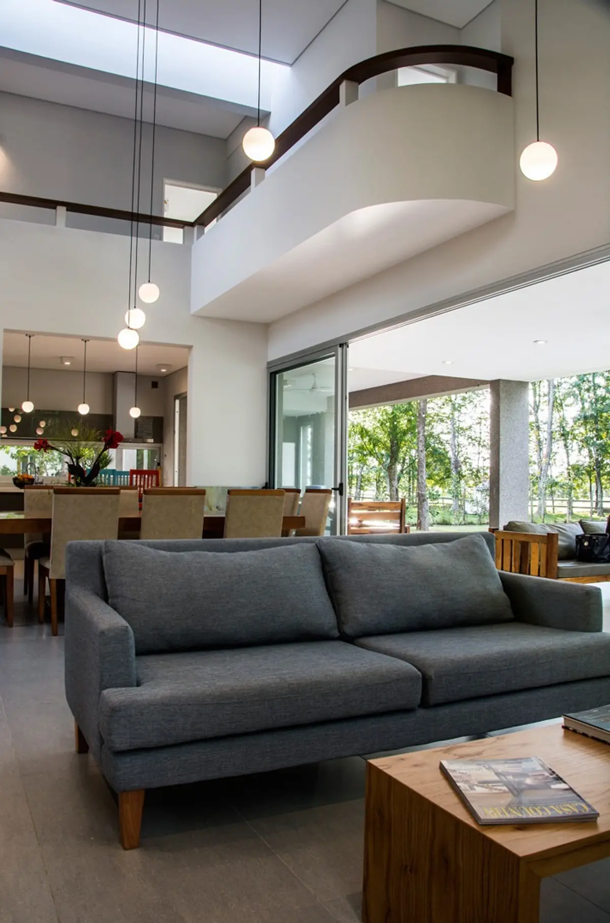 living moderno con sofa gris y doble altura luminosa — proyecto Casa 18, por Parrado Arquitectura
